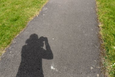 Parlak güneşin altında fotografileri alan birinin yakın görüntüsü.