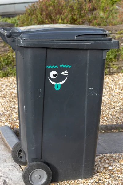 Een Close Van Een Zwarte Vuilnisbak Met Een Grappige Sticker — Stockfoto