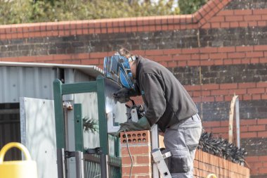 Bristol-Nisan-2020-İngiltere, ana güvenlik kapısına metal boru döşeyen bir adamın yakın görüntüsü.