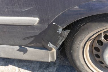 Hasarlı tekerlek kemerini onarmak için siyah bant kullanan bir arabanın yakın görüntüsü. 