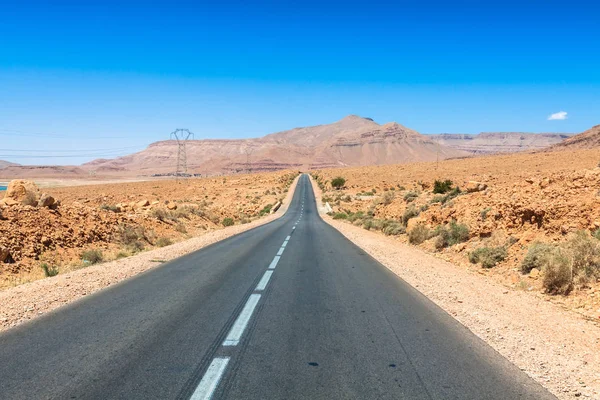 Nekonečné silnice v poušti Sahara s modrou oblohu, Maroko Afrika — Stock fotografie