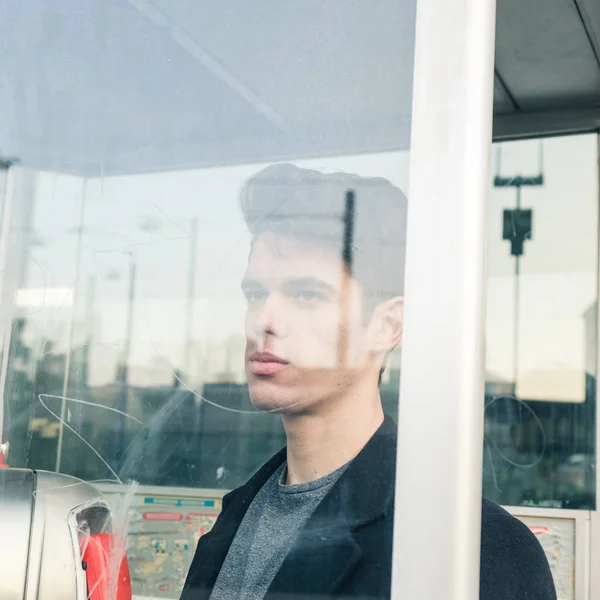 Beautiful young man posing in a phone booth — Stock Photo, Image