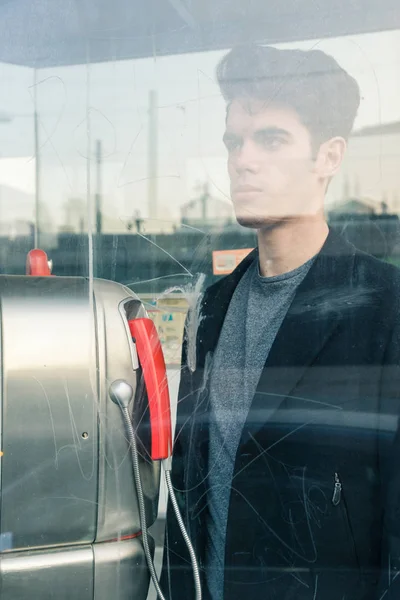 Beautiful young man posing in a phone booth — Stock Photo, Image