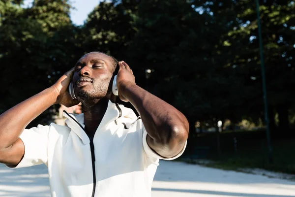 Black man listening to music in a city park — Stock Photo, Image