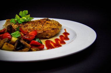 Siyah arka planda fırında sebzeli domuz filetosu.