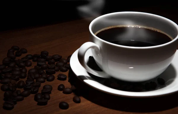 Tasse Kaffee und Bohnen auf dem Tisch — Stockfoto