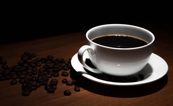 Чашка кофе и бобы на столе — стоковое фото