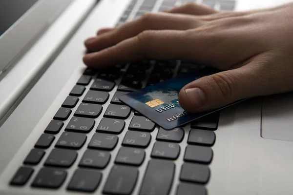 Mãos segurando um cartão de crédito e usando computador portátil — Fotografia de Stock