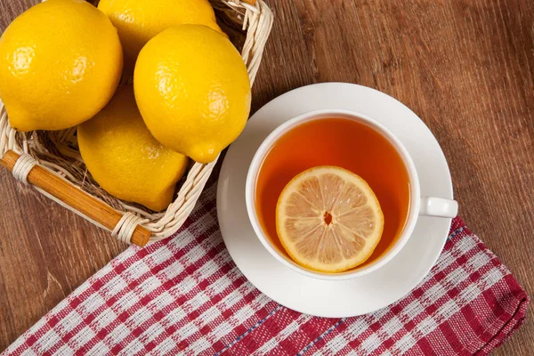 Bodegón de limones frescos en una canasta y una taza de té — Foto de Stock