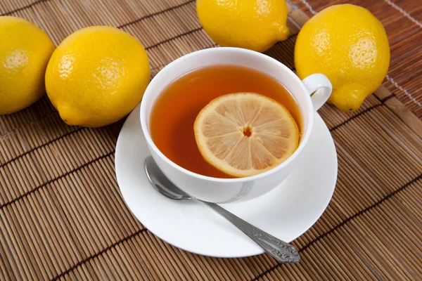 Bodegón de limones frescos en una servilleta de bambú con taza de té — Foto de Stock