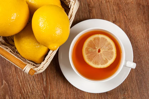 Bodegón de limones frescos en una canasta y una taza de té — Foto de Stock