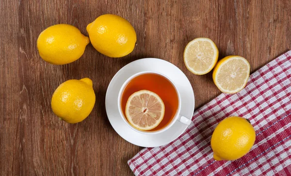 Bodegón de limones frescos en una mesa de madera con taza de té — Foto de Stock