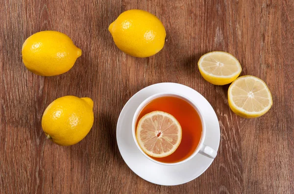 Bodegón de limones frescos en una mesa de madera con taza de té — Foto de Stock