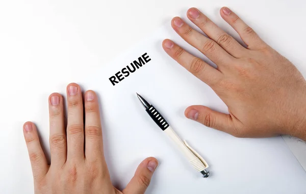 Man's hands on resume form and pen — Stock Photo, Image
