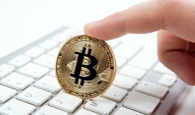 Beyaz klavye ve bir adamın elinde altın sikke bitcoin