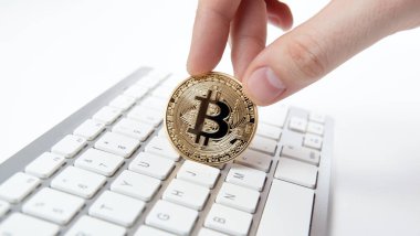 Beyaz klavye ve bir adamın elinde altın sikke bitcoin