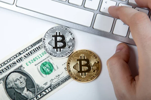 Duas moedas de bitcoin e uma nota de dólar e mão humana no laptop — Fotografia de Stock