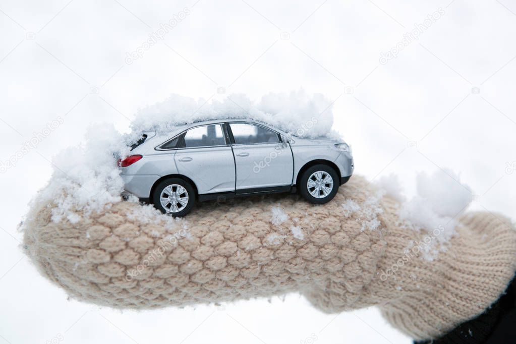 girl holds in her hand model of car with snow