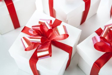 Beyaz şenlikli hediye kutuları ile bir beyaz üzerine kırmızı yay