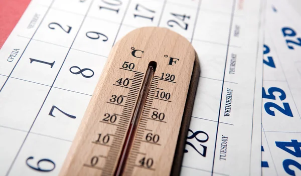 Термометр на белом столе на листах настенного календаря — стоковое фото