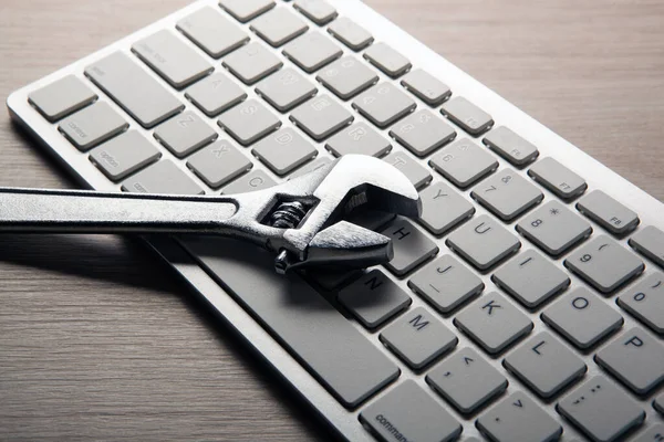 Grote verstelbare moersleutel en een computer toetsenbord close-up — Stockfoto