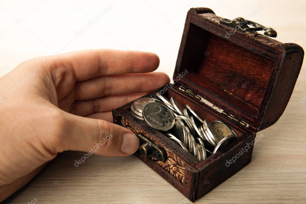 human hand next to a small chest of Russian ruble coins