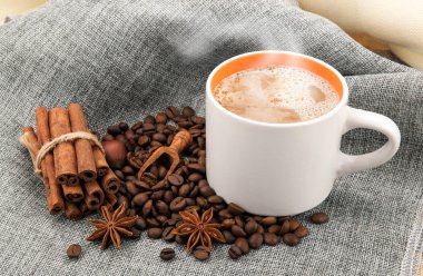 Renkli kumaş üzerinde bir fincan sütlü kahve ve kavrulmuş kahve.