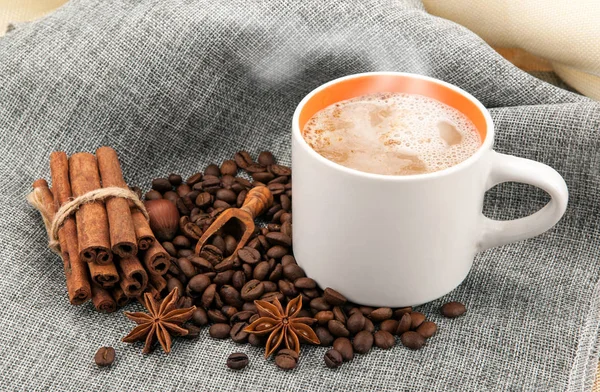 Tasse Milchkaffee auf farbigem Tuch und gerösteten Kaffeebohnen clo — Stockfoto