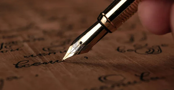 木製の机の上にインクの文字が書かれた紙で手に噴水のペン — ストック写真