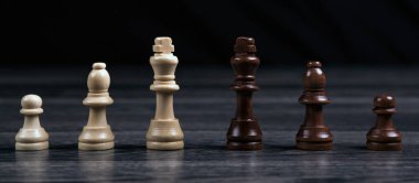 Satranç kralları ve çeşitli satranç taşları tahta bir arka planda durgun bir hayat olarak sıralanmış.