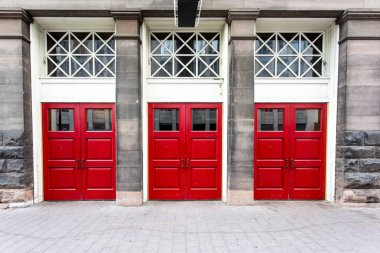 Eski bir tuğla bina üç parlak kırmızı Çift Kişilik kapıları.