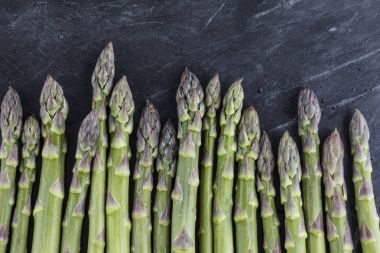 Taze kuşkonmaz kadar bir çizgi bir karanlık taş yüzey ızgara için bekleyen oturur.