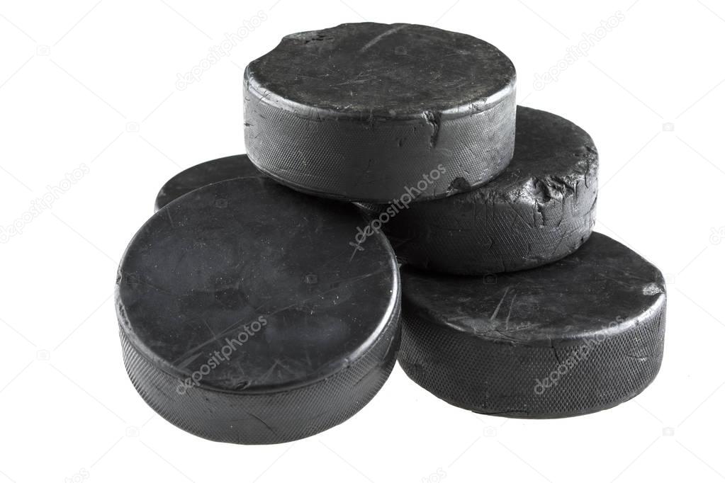 A stack of five used hockey pucks isolated on a white background.