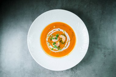 Taş bir tezgahın üstünde taze pişmiş sıcak çorba. Karides ve sebzeli balkabağı çorbası..