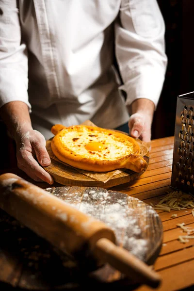 Şef tarafından tutulan lezzetli, taze pişmiş khachapuri. Gürcistan mutfağı.