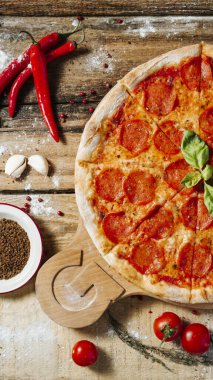 Lezzetli ev yapımı peynirli pizza, taze sebzeler ve ahşap masada pepperoni..