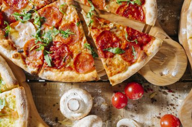 Lezzetli ev yapımı peynirli pizza, taze sebzeler ve ahşap masada pepperoni..