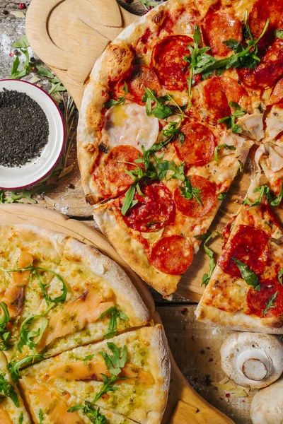 Taze sebzeli, biberli ve ahşap masada jambonlu nefis ev yapımı peynirli pizza. Yakınlardaki somon pizzası parçası..