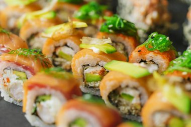 Lezzetli suşi dürümlerinin makro çekimi. Somon dilimleri, avokado ve yeşiller..