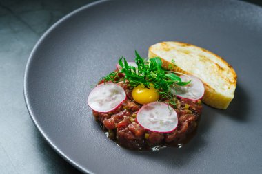 Yumurta sarısı, turp dilimi ve sebzeli nefis sığır etli tartar. Kapat..