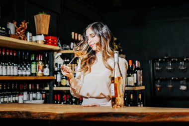 Experienced elegant sommelier woman tastes wine in restaurant. Checking taste, colour, sediments of wine. Space for text.