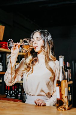 Tecrübeli zarif şarap garsonu kadın restoranda kırmızı şarap tadıyor. Tadı, rengi, şarap tortuları kontrol ediliyor..