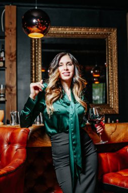 Bar tezgahının yanında şarap kadehi olan zarif genç bir kadın..
