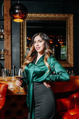 Bar tezgahının yanında şarap kadehi olan zarif genç bir kadın..