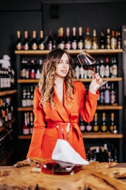 Tecrübeli zarif şarap garsonu kadın restoranda kırmızı şarap tadıyor. Tadı, rengi, şarap tortuları kontrol ediliyor.