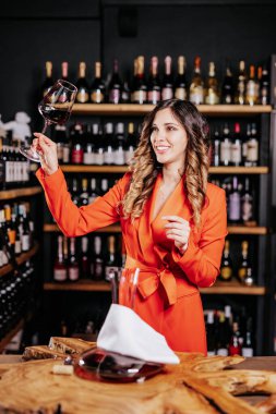 Tecrübeli zarif şarap garsonu kadın restoranda kırmızı şarap tadıyor. Tadı, rengi, şarap tortuları kontrol ediliyor.