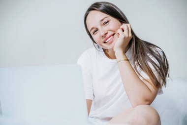 Genç, neşeli bir kadın evde çalışmak için dizüstü bilgisayar kullanıyor. Metin için boşluk.