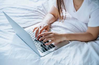 Yatağında dizüstü bilgisayar kullanan bir kadın