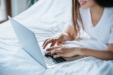 Yatağında dizüstü bilgisayar kullanan bir kadın