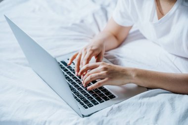 Yatağında dizüstü bilgisayar kullanan bir kadın